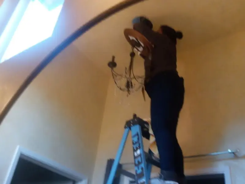 Electrician installing a chandelier in a Bristol residence